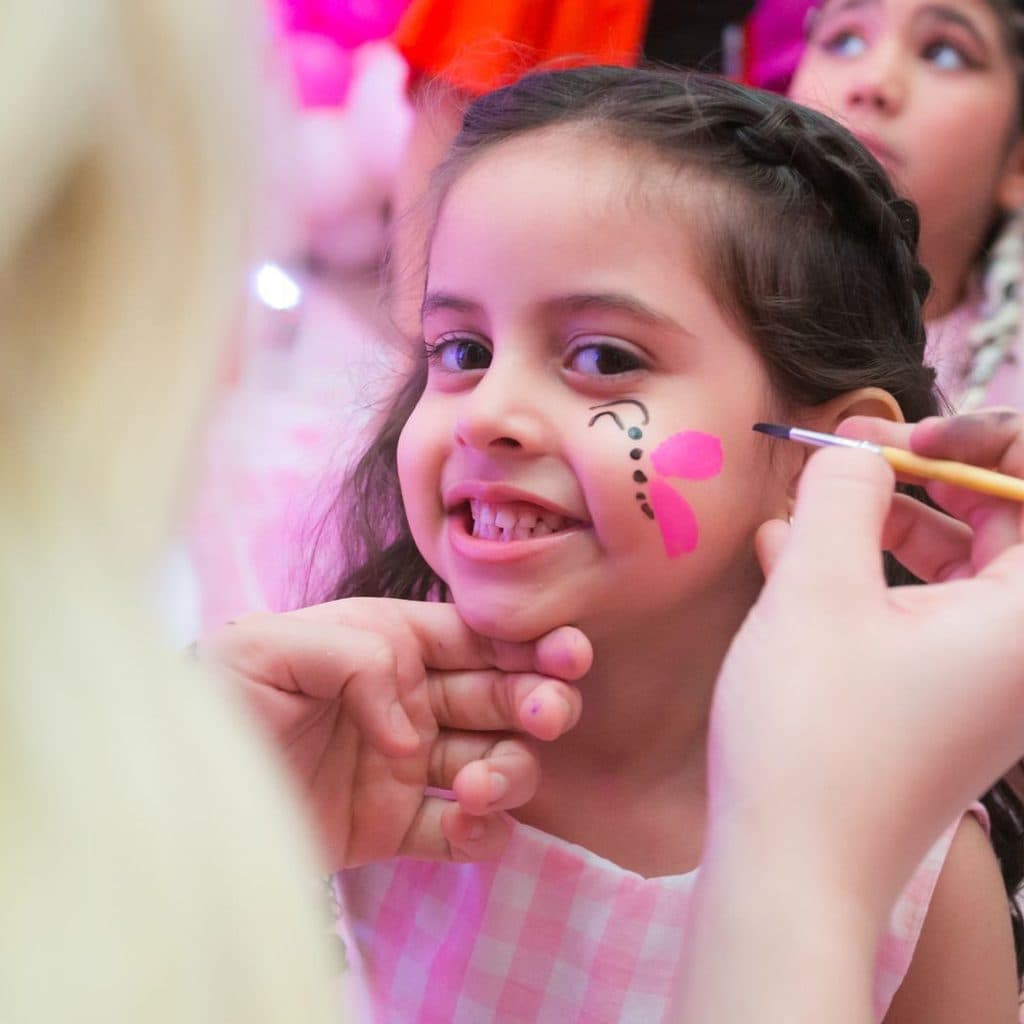 Pintura facial sendo feita em criança durante festa infantil em Guarujá